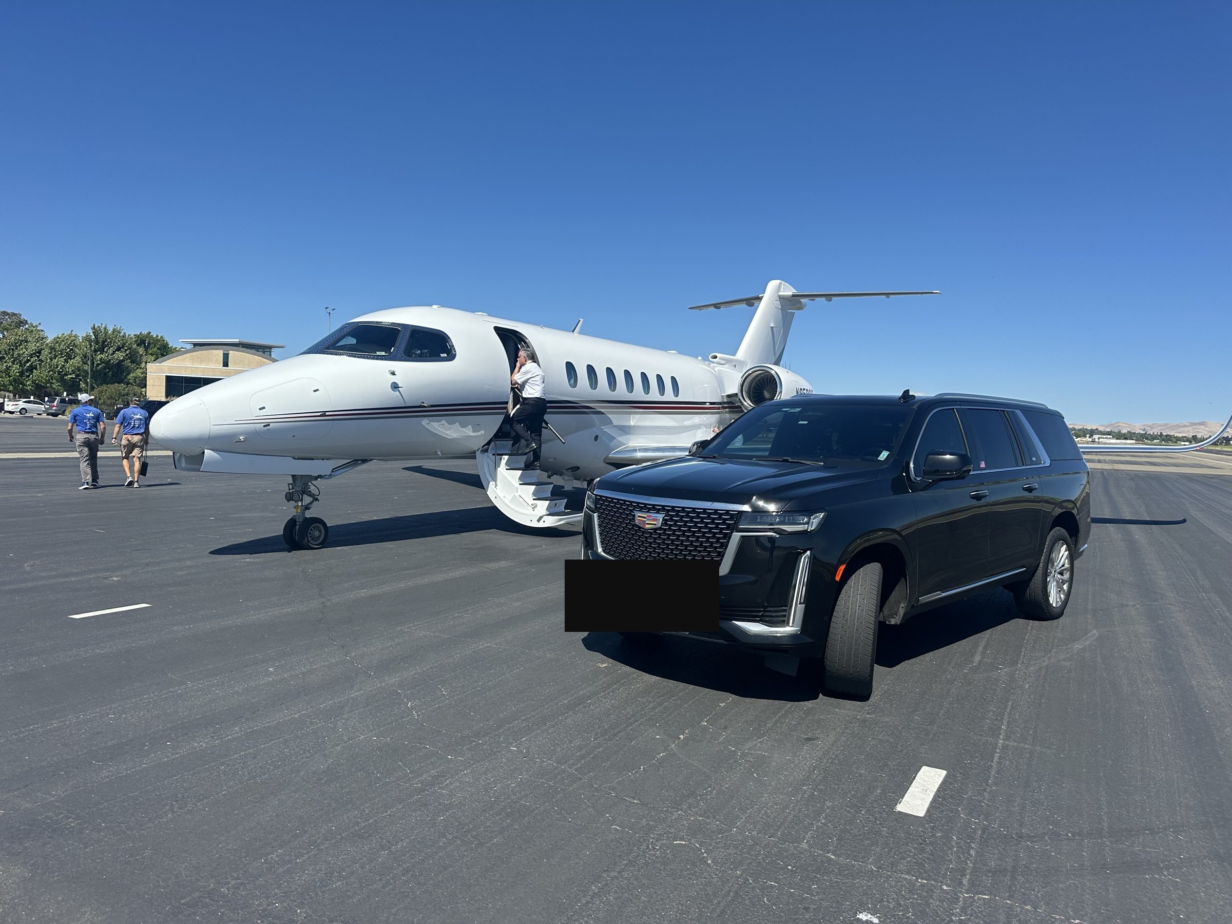 Black Cadillac Escalade SUV beside a private jet